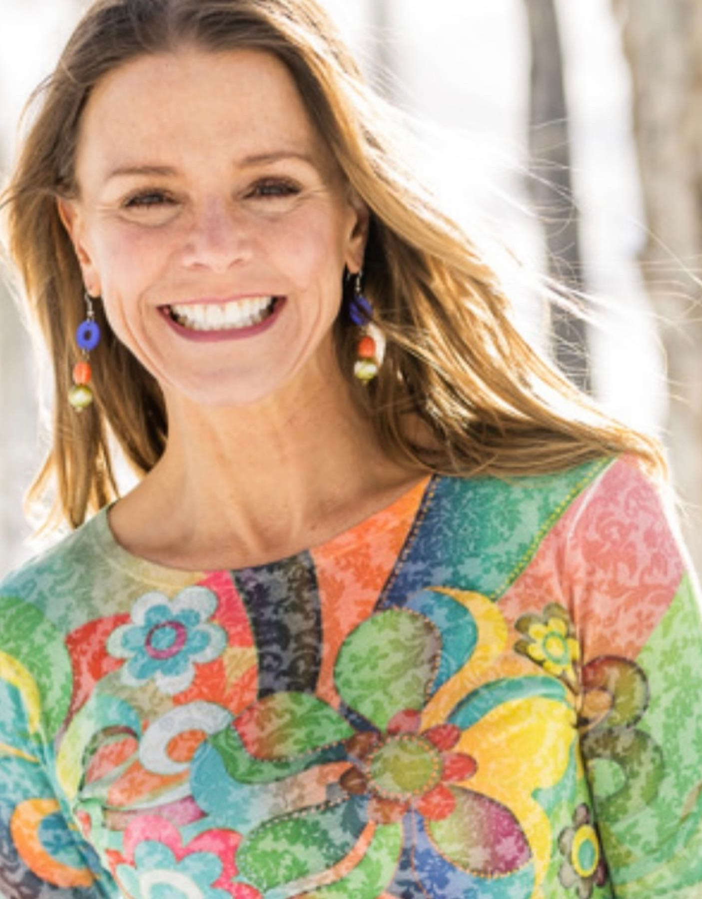 Portrait of Kelley Dole smiling outdoors in a colorful floral top